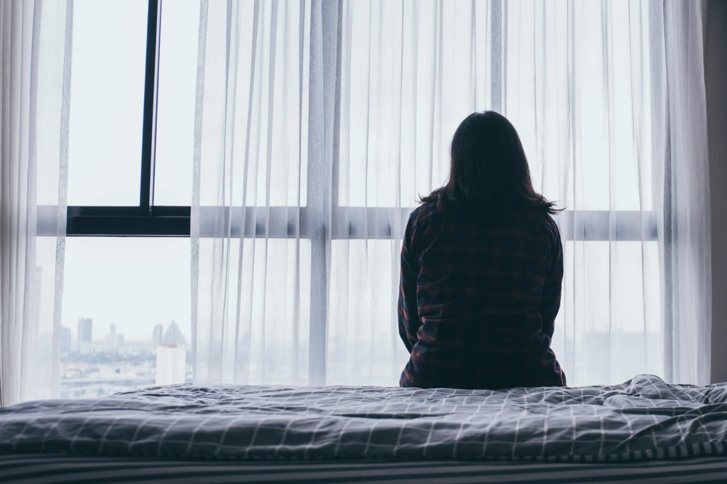 Sad woman sitting on a bed.