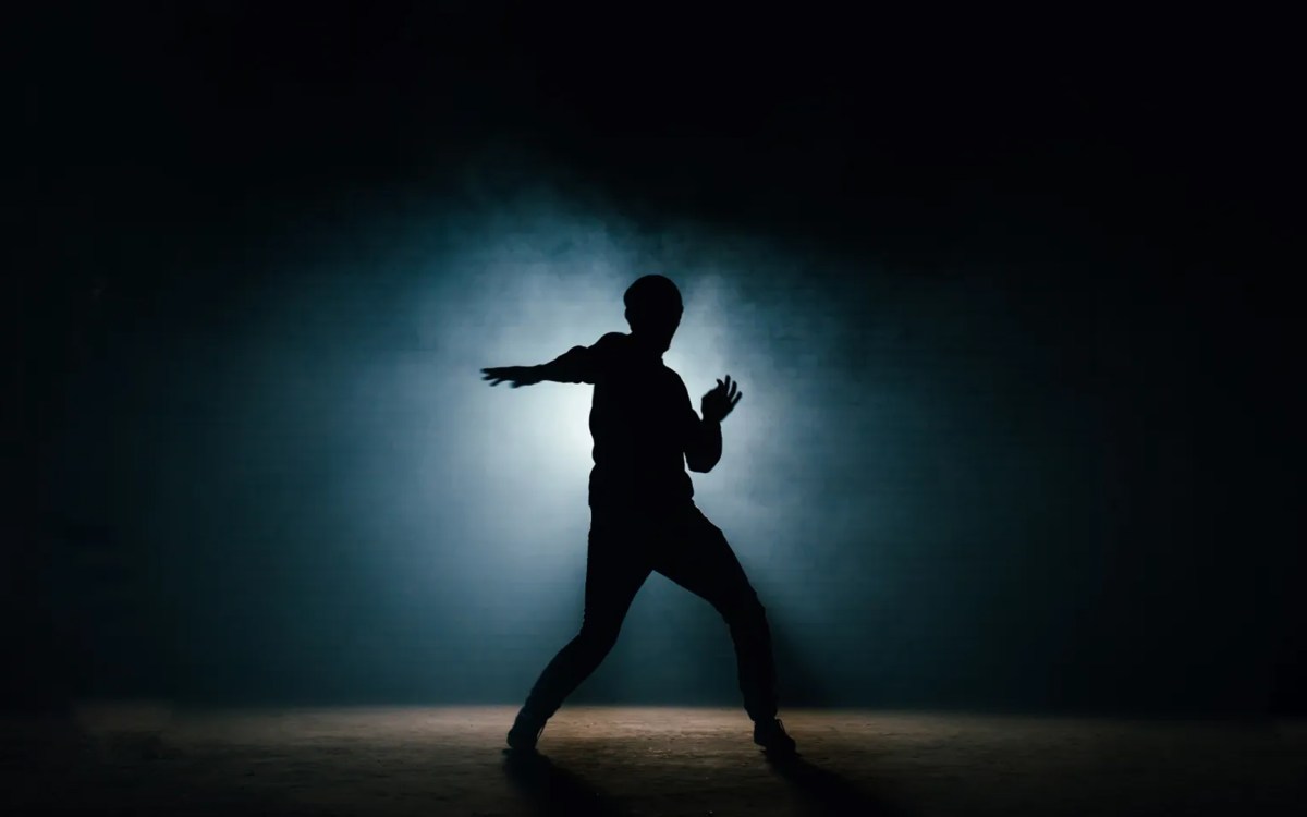 A dancer is silhouetted against a dark background.