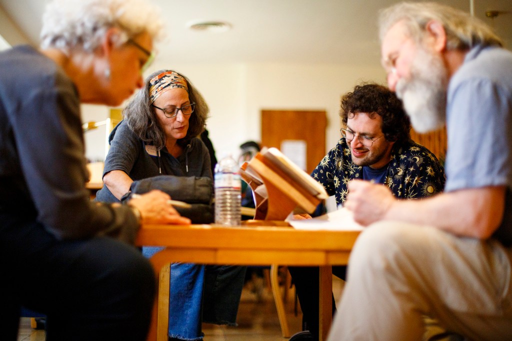 Writers Maria Lisella, Julia Lisella, Josh Kurtz, and Kenny Likis circle a table in Harvard's Woodberry Poetry Room.