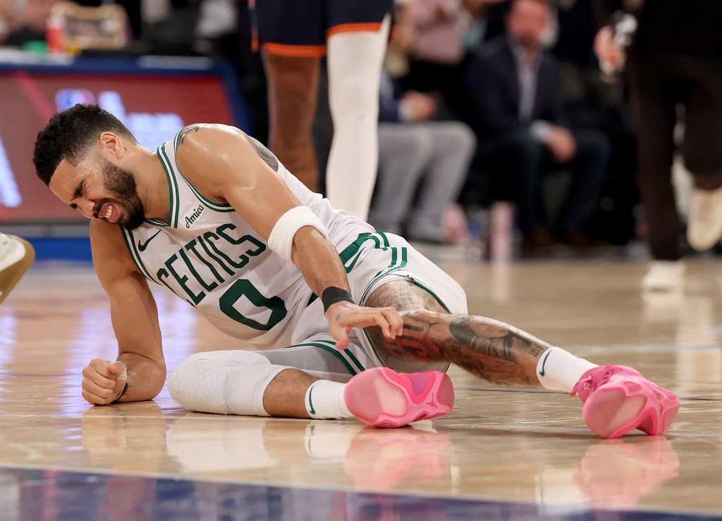 Jayson Tatum of the Boston Celtics clutches his leg on the court after injury during playoffs game vs. the New York Knicks.
