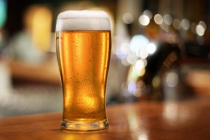 Glass of chilled beer on wooden bar table.